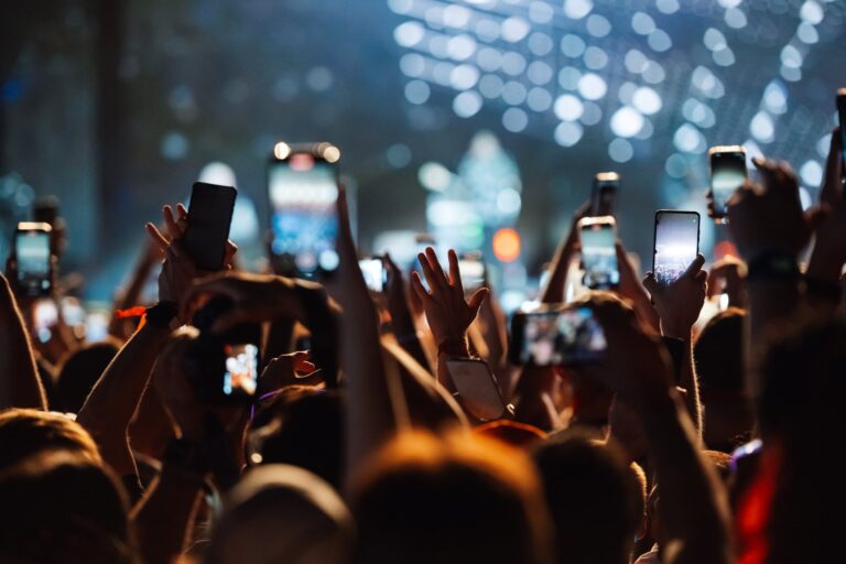 Concert crowd holding up smartphones to record, each phone a new source of information