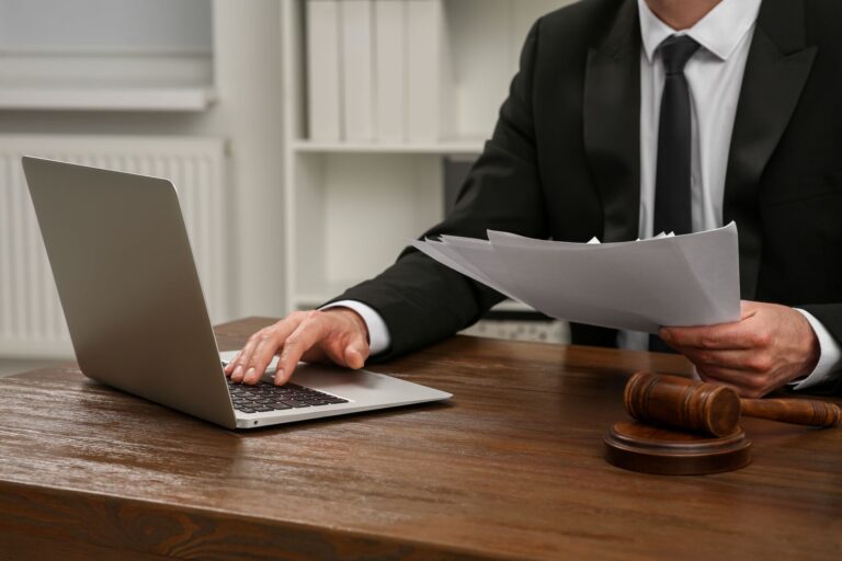 Professional researching federal court records on a laptop, with documents and a judge’s gavel on the desk
