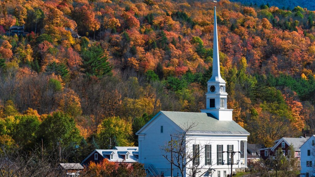 The white Stowe Community Church steeple against a hillside of autumn foliage in Stowe, Vermont, home of Competitive Futures