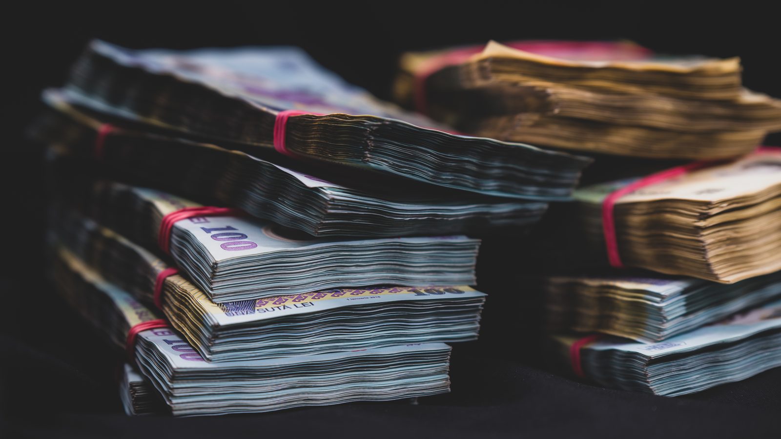 Stacks of mixed-currency banknotes bound with rubber bands