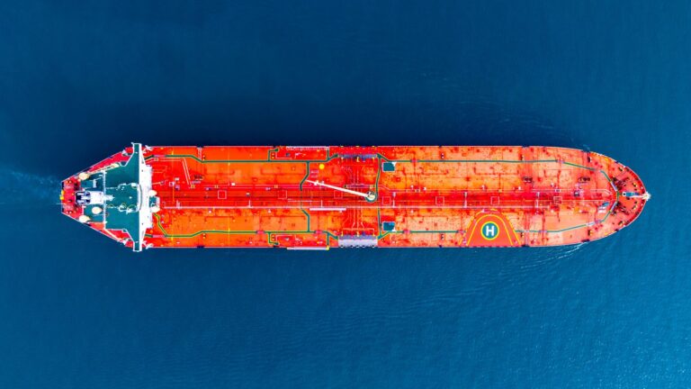 Aerial view of an orange oil tanker crossing deep blue water