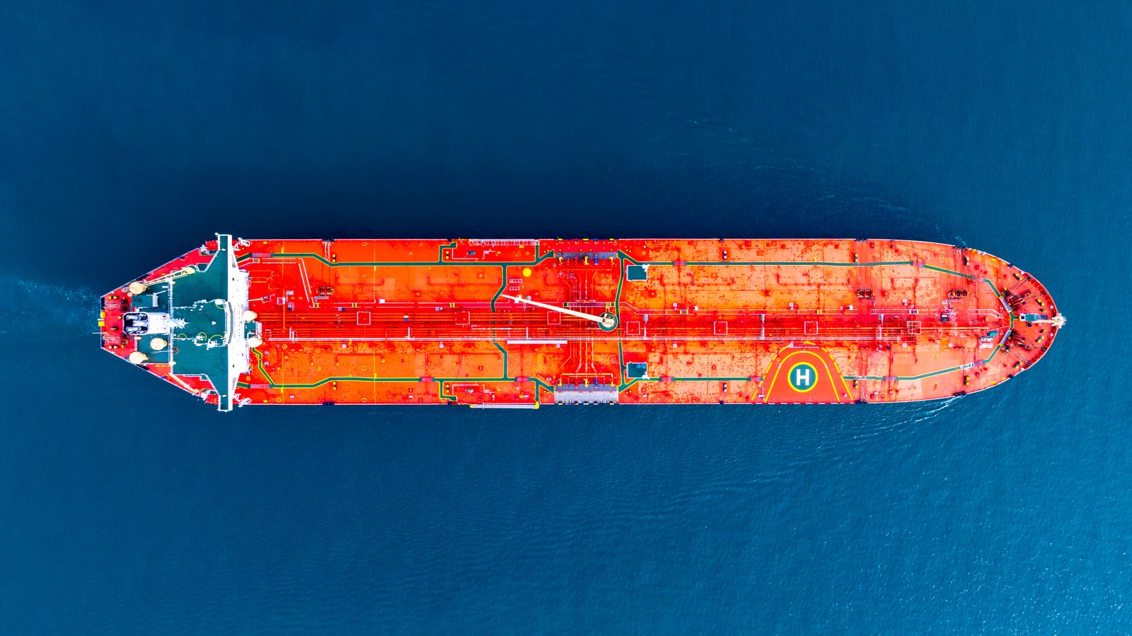 Aerial view of an orange oil tanker crossing deep blue water