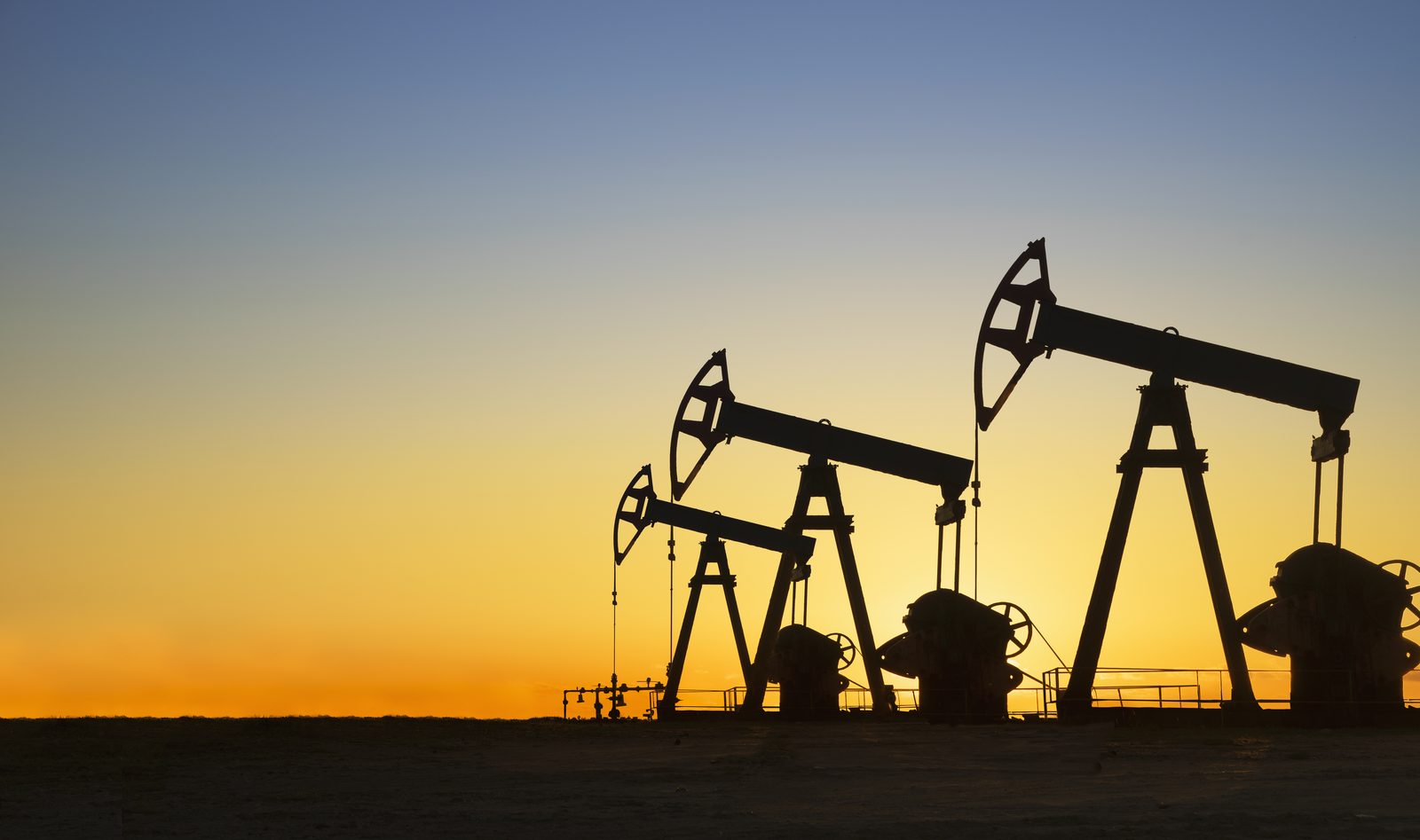 Oil pumpjacks silhouetted against a Texas sunset, symbol of the shale boom that upended peak oil forecasts